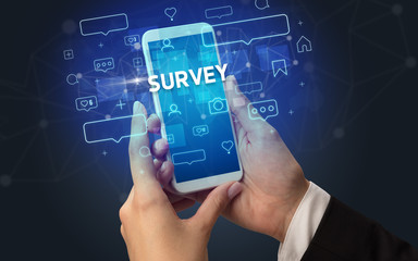 Obraz premium Female hand typing on smartphone with SURVEY inscription, social media concept