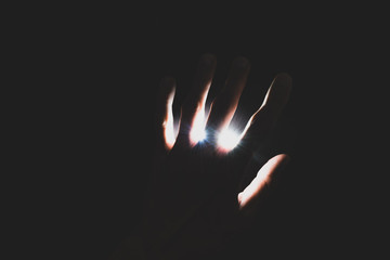 Abstract background of hand covers illuminated light or power bright source in dark background with copy space