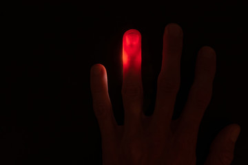 Obraz premium Abstract background of Illuminated and transparent red finger with visible vein on black background with copy space