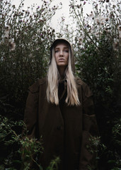 sad girl in a brown hooded cloak stands among the tall grass
