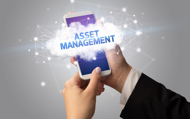 Female hand touching smartphone with ASSET MANAGEMENT inscription, cloud business concept