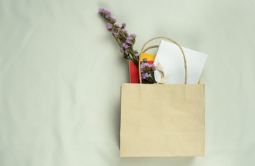purple flower and notebook in recycled paper shopping bag business and marketing background