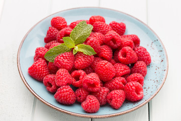 Fresh raspberries in a plate on a  vintage background.