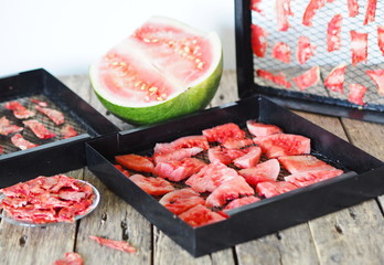 Autumn harvesting season. The process of preparing sweet treats for future use, from a whole green watermelon to dried pieces of homemade dried watermelon fruit on a plate.