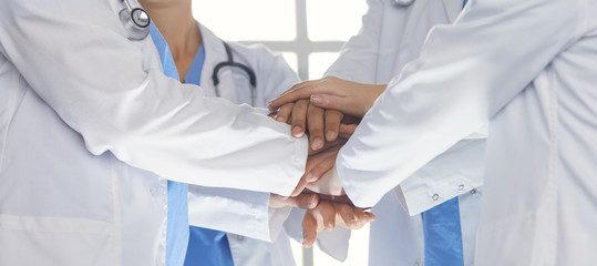 Team of medical workers holding hands together indoors, above view. Unity concept