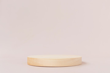 Wooden textured round low podium on a light background. Background for product photography, organic cosmetics, eco products. Geometric shape for product presentation.