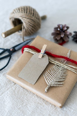 Fototapeta na wymiar Ein Geschenkpaket weihnachtlich verpackt mit roter Schnur auf einem Leinen Tischtuch. Nahaufnahme, golden, Schere.