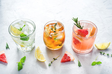 Summer refreshing fruit drinks with ice on a grey background.