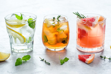 Summer refreshing fruit drinks with ice on a grey background.