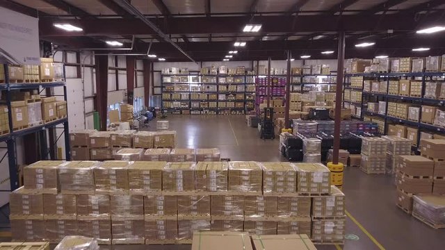 Wide aerial shot of stacks of boxes inside industrial warehouse