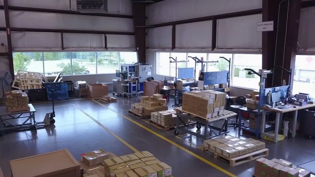 Aerial push-out shot of boxes and equipment in industrial warehouse