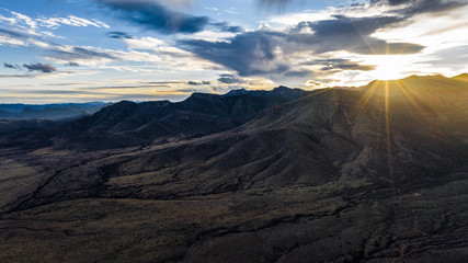Aerial view and panorama of Arizona mountain ranges during sunset with clouds and sun