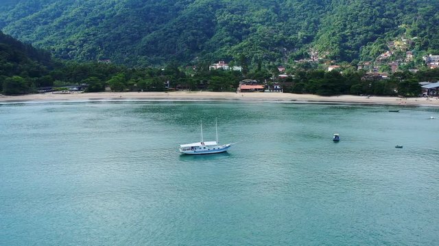 Aerial: drone shot in brazil santa rita beach  ubatuba with view to yacht park sailboats in on the road that passes the sea and the jungle sunset sao paulo san pablo litoral north escuna lancha