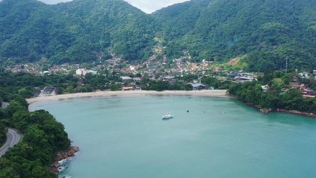 Aerial: drone shot in brazil santa rita beach ubatuba with view to yacht park sailboats in on the road that passes the sea and the jungle sunset sao paulo san pablo litoral north escuna lancha
