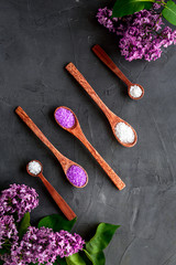 Pattern of spa sea salt in spoons with lilac flowers. Above view