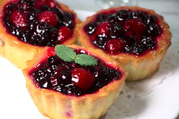 Cupcake basket, with berries on a white plate. Tartlet with custard and berry jelly, close-up photo.