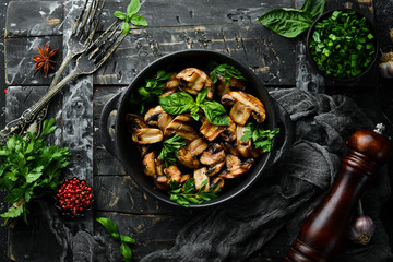 Food. Grilled mushrooms with basil on a black stone plate. Top view. Free space for your text.
