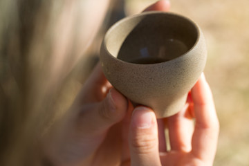 Ceramic bowls made of clay on a wooden background. .The girl is drinking Chinese tea.