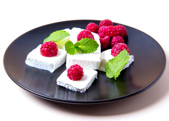 Ice cream with raspberries and mint on a black plate, white background