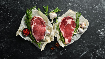 Dry-aged raw meat steak with spices, pepper and rosemary. Top view. Free space for your text.