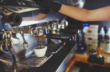 Barista wearing medical latex black gloves,preparing coffee drink with espresso machine in coffee shop cafe.Blurred image, selective focus