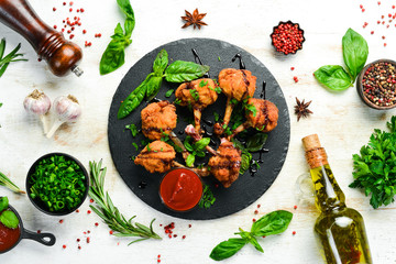 Food. Baked Buffalo Chicken Wings with Ketchup and Balsamic Sauce on a Black Stone Plate. Top view. Free space for your text.