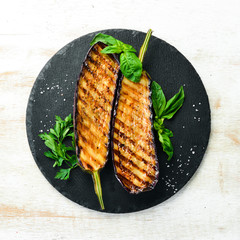 Grilled eggplant with basil on a black stone plate. Top view. Free space for your text.