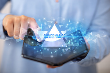 Businessman holding a foldable smartphone with GOVERNANCE inscription, business concept