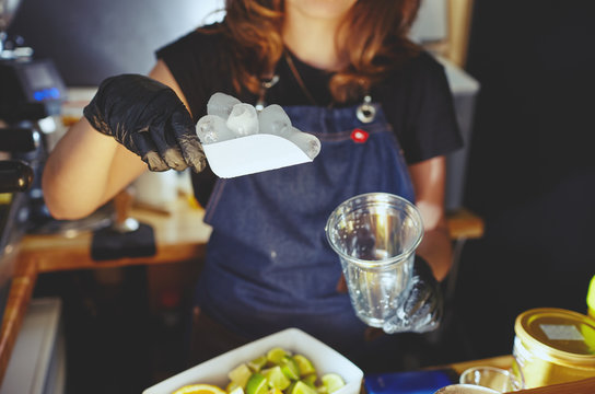 Bartender wearing medical latex black gloves, making mojito cocktail.Pieces of ice,ingredient for cooling drinks in bar.Blurred image, selective focus