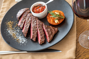 medium rare fried steak on a black plate, in the interior with natural light