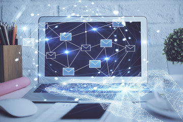 Desktop computer background in office and flying envelops hologram drawing. Double exposure. Electronic mail concept.