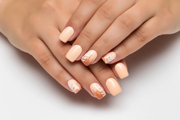 Peach wedding manicure with gold sequins and white branches, leaves on square long nails close-up on a white background.