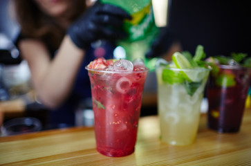 Bartender wearing medical latex black gloves,making mojito cocktail.Process of bartending in bar.Blurred image, selective focus