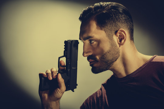 Closeup photo of young brutal special agent holding gun