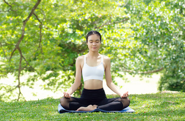 Young woman practicing yoga in the nature, Asian woman is practicing yoga in city park.