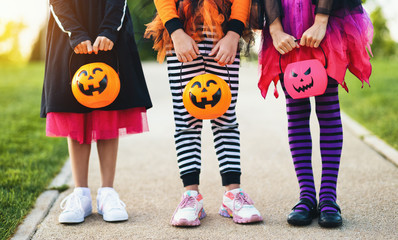 Happy Halloween! legs of funny children in carnival costumes outdoors - obrazy, fototapety, plakaty