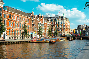 Canal in Amsterdam with pleasure boat and historic buildings