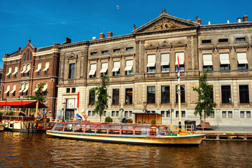 Amsterdam, Netherlands - July 2019: Pleasure boat beside pier on the Amstel river in the Amsterdam center