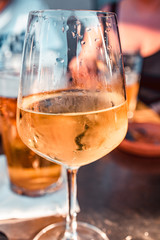 Close up of a summer aperitif with friends in Milan with white wine chalice and pints of fresh beer. Snacks in the background. Vertical cut.
