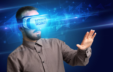 Businessman looking through Virtual Reality glasses with DATABASE SECURITY inscription, cyber security concept