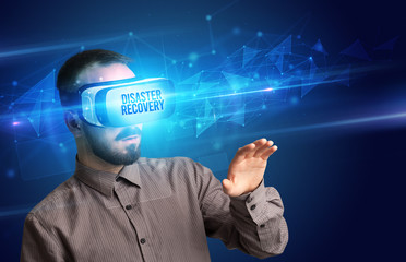 Businessman looking through Virtual Reality glasses with DISASTER RECOVERY inscription, cyber security concept