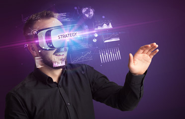 Businessman looking through Virtual Reality glasses with STRATEGY inscription, new business concept