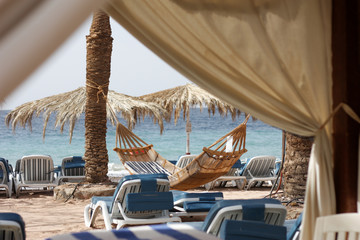 Fototapeta na wymiar Striped hammock at the resort beach.