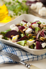 Vegetarian salad with beets and feta. Served in a square bowl. Front view.