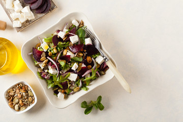 Vegetarian salad with beets and feta. Served in a square bowl. Top view.