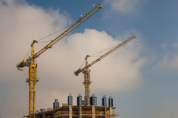 Construction site with cranes against the cloudy sky