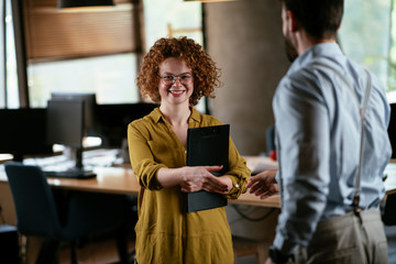 Colleagues in office. Businesswoman and businessman handshake in office
