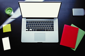 Top view of workplace with open laptop, colorful notebooks and stickers, computer with blank copy...