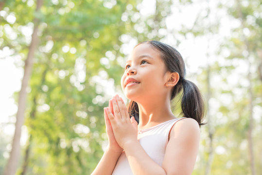 cute little girl hands praying to god with the bible in the morning on nature background.  little asian girl hand praying for thank god. copy space. spirituality and religion faith hope concept.