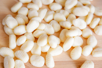Traditional gnocchi, handmade italian pasta, with tomatoes on wooden table, natural light